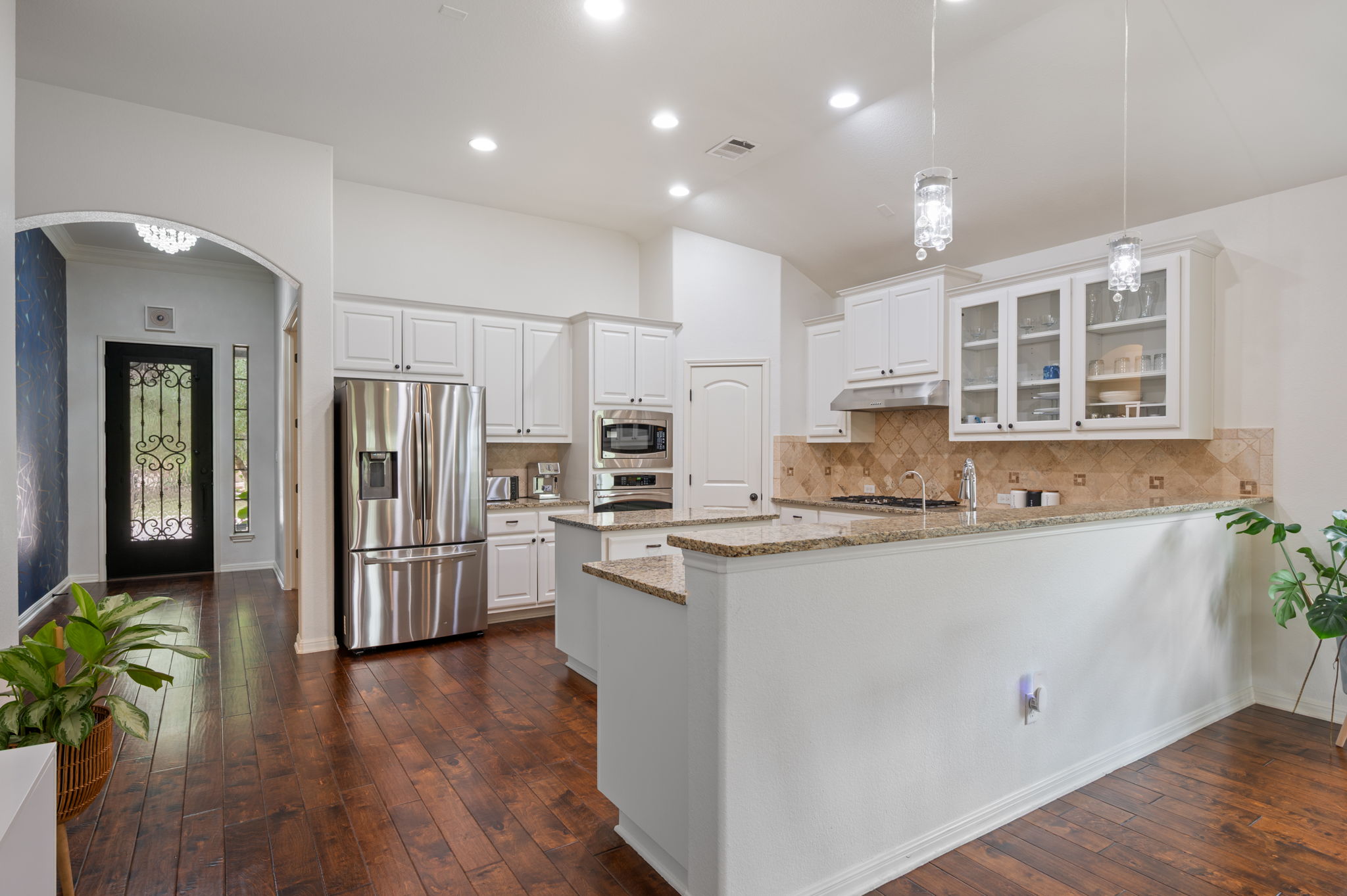 4220 Tambre Bend Austin, TX 78738 - Photo 10 of 28 Kitchen featuring light stone countertops, white cabinets, glass insert cabinets, stainless steel appliances, and tasteful backsplash