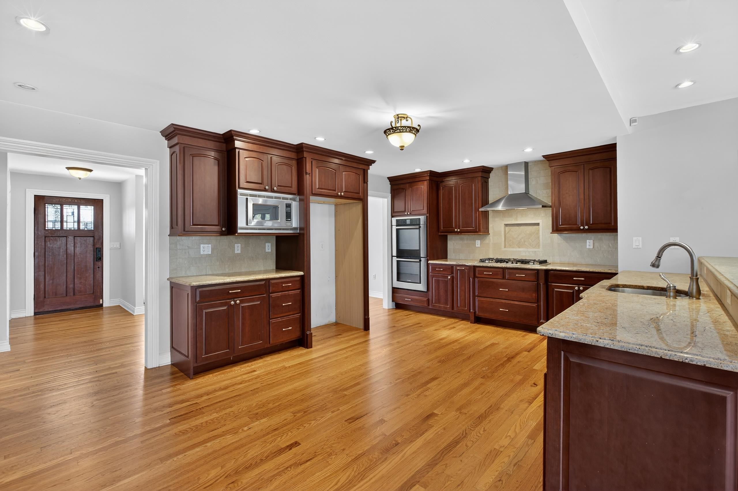 33 Georgia Drive Wayne, NJ 07470 - Photo 5 of 36 a large kitchen with stainless steel appliances wooden floors and wooden cabinets
