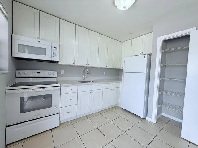 a kitchen with white cabinets and white appliances