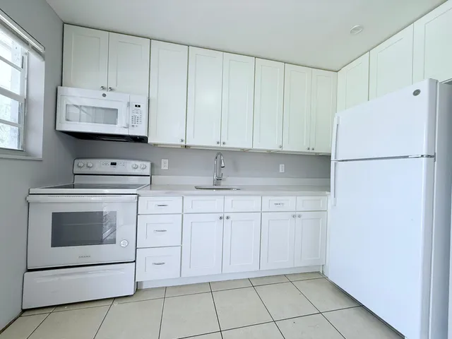 a kitchen with white cabinets and white appliances