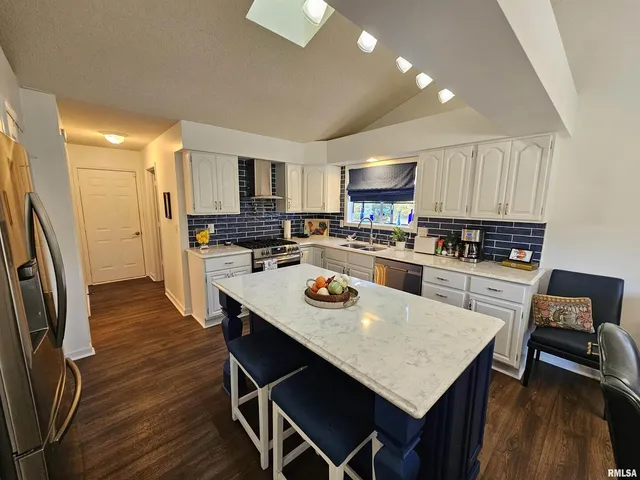 a kitchen with stainless steel appliances a table chairs and a refrigerator