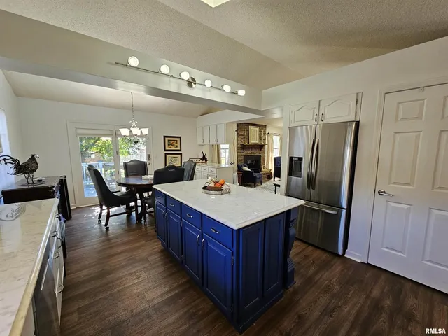 a kitchen with kitchen island wooden floors appliances and dining table