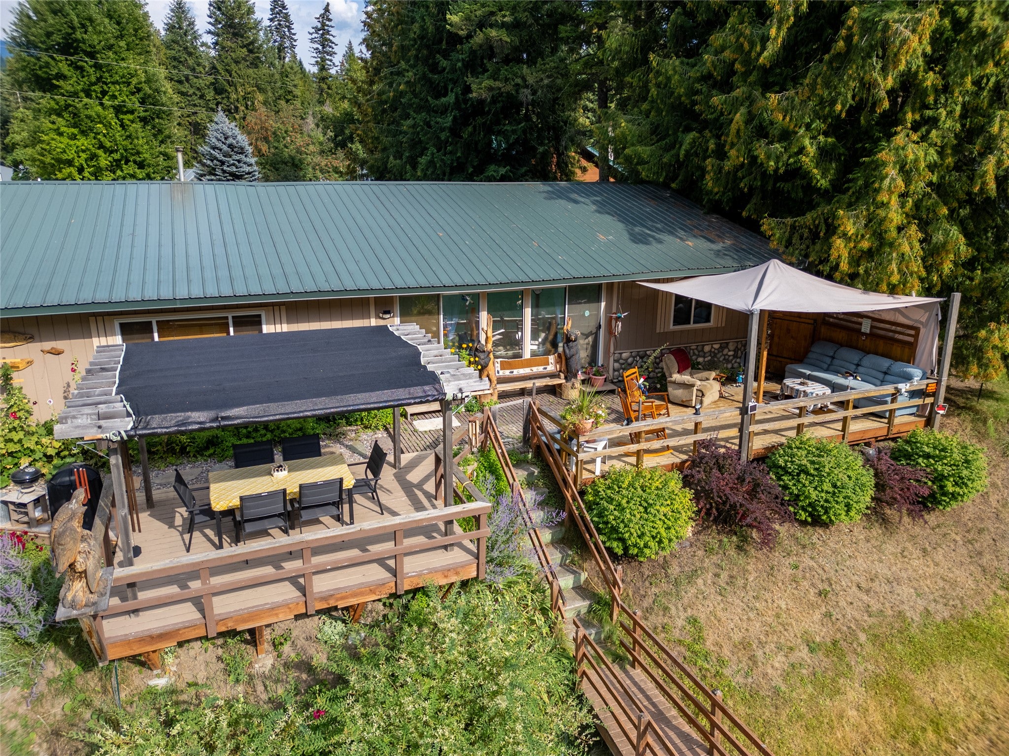 644 Waterfront Road Troy, MT 59935 - Photo 13 of 66 View of back of house featuring outdoor lounge area, a wooden deck, a metal roof, and outdoor dining space