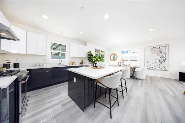 a large white kitchen with lots of counter space a sink wooden cabinets and appliances