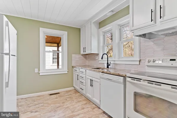 a kitchen with granite countertop a sink stove and cabinets