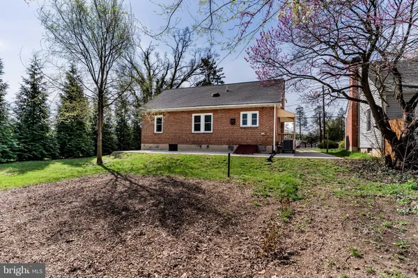 a view of a house with a yard and large trees