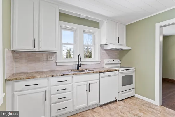 a kitchen with granite countertop a sink stainless steel appliances and cabinets