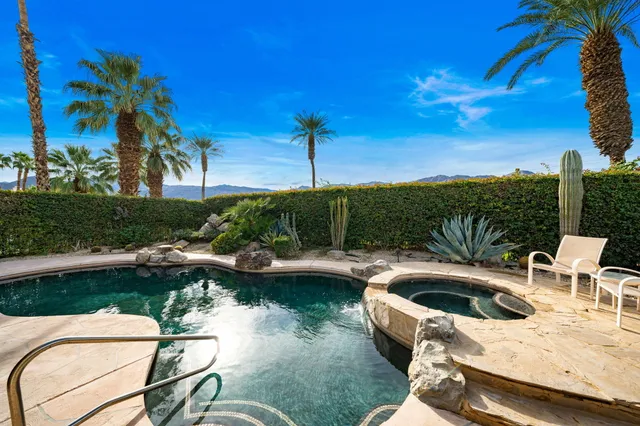 a view of a swimming pool with lawn chairs under an umbrella