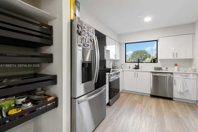 a kitchen with stainless steel appliances a sink and wooden floor