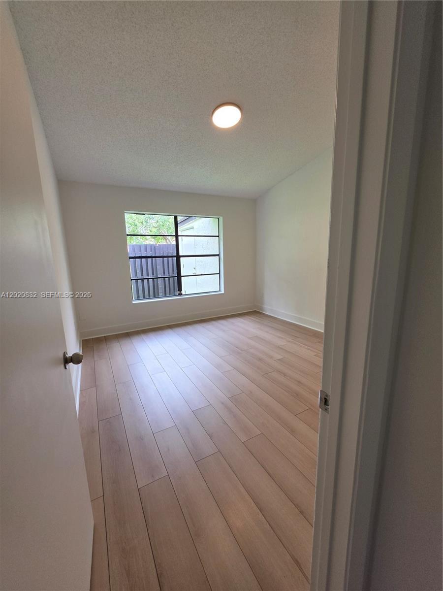 15240 Southwest 45th Terrace, Unit 54F Miami, FL 33185 - Photo 33 of 48 an empty room with wooden floor and windows