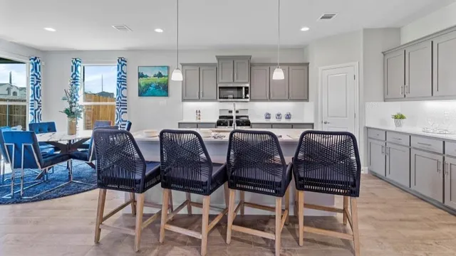 a kitchen with stainless steel appliances kitchen island granite countertop a table chairs sink and cabinets