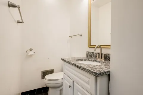 a bathroom with a granite countertop sink a toilet and a mirror