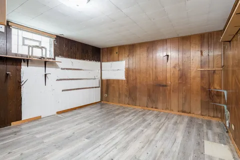 an empty room with wooden floor closet and windows