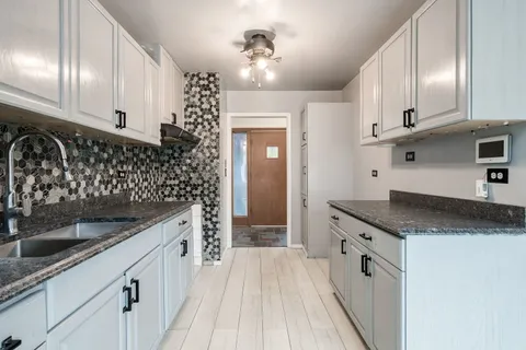 a kitchen with granite countertop a sink stove and cabinets