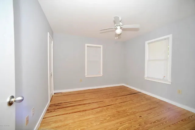 an empty room with windows and fan