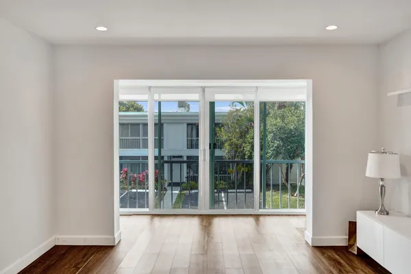 a view of empty room with wooden floor and fan