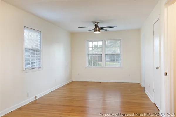 a view of empty room with wooden floor and fan