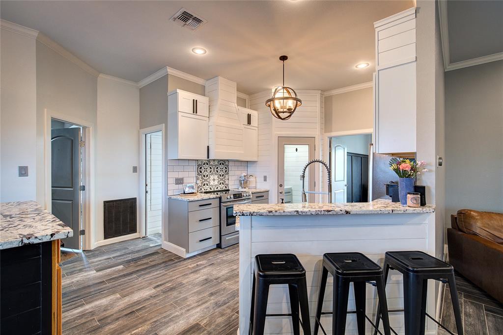 2027 Park Springs Road Sulphur Springs, TX 75482 - Photo 12 of 39 a kitchen with granite countertop a stove a kitchen island with a dining table and chairs
