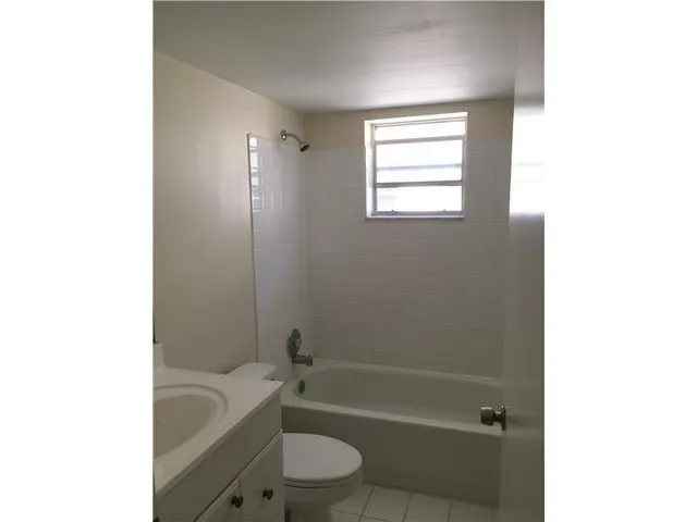 a bathroom with a granite countertop bathtub shower sink vanity and toilet