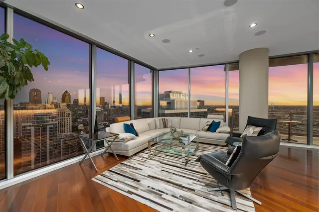 a living room with furniture large windows and wooden floor