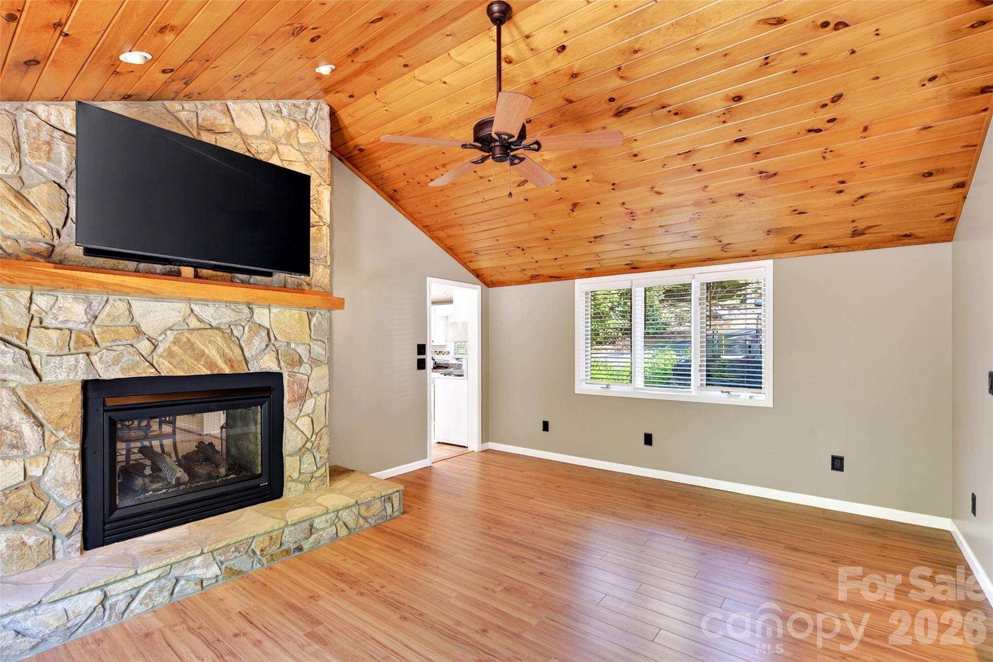 334 Harbor Lake Road Newland, NC 28657 - Photo 11 of 48 a living room with a fireplace a flat screen tv and a ceiling fan