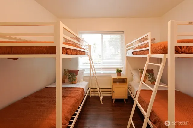 a view of an empty room with wooden floor and furniture
