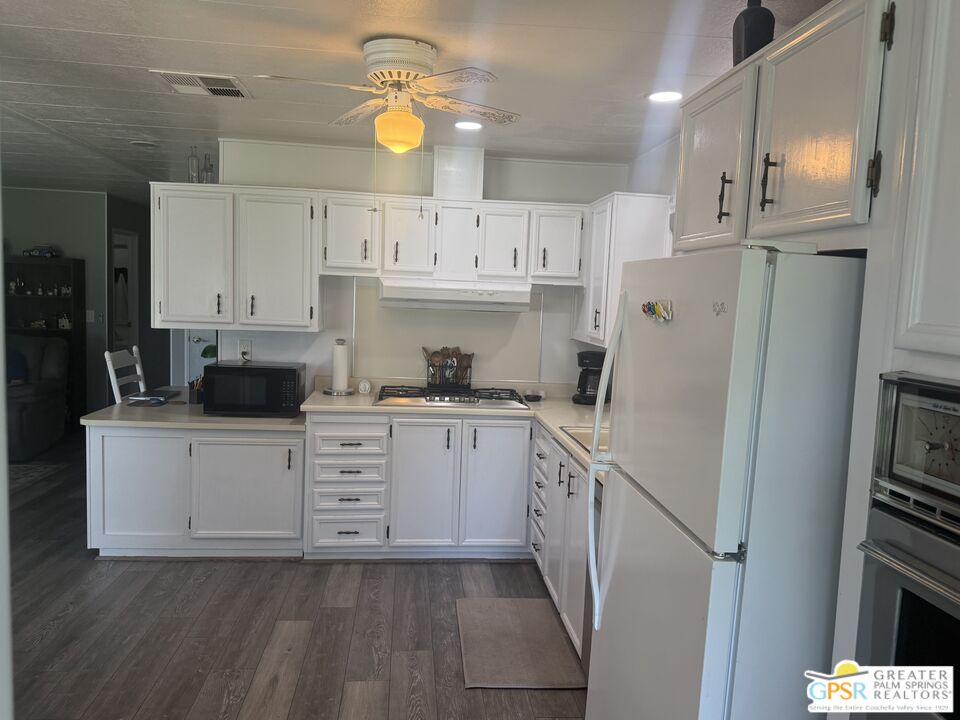15500 Bubbling Wells Road, Unit 286 Desert Hot Springs, CA 92240 - Photo 12 of 50 a kitchen with white cabinets and white appliances