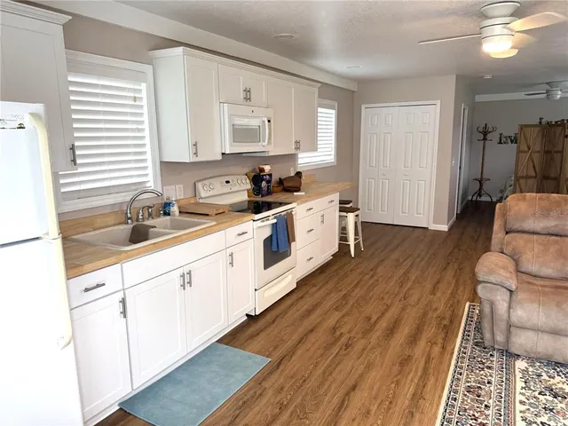 a large kitchen with a lot of white cabinets and wooden floor