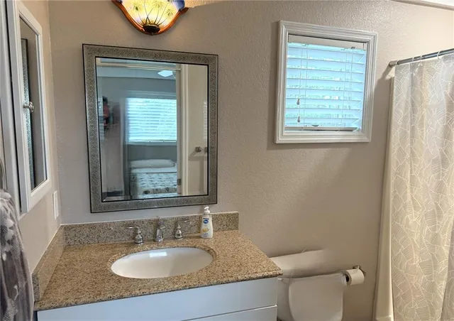 a bathroom with a granite countertop sink toilet and mirror