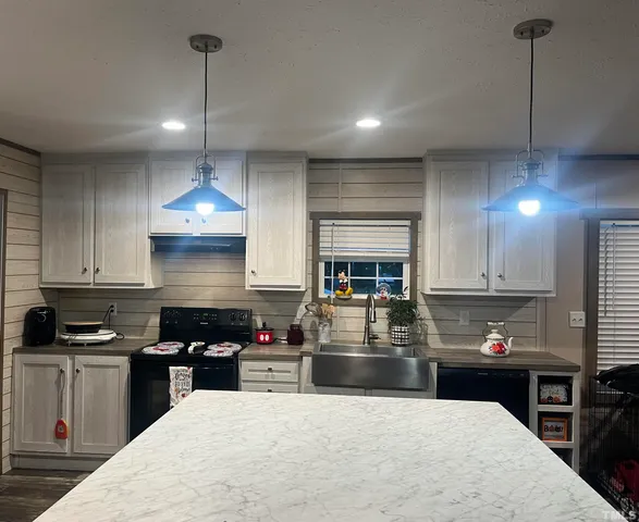 a kitchen with kitchen island granite countertop a sink a counter space appliances and cabinets