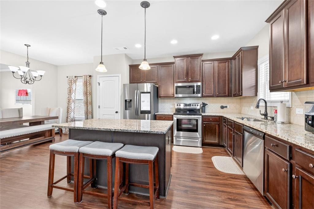 860 Tranquil Way Hampton, GA 30228 - Photo 14 of 54 a open kitchen with stainless steel appliances granite countertop a stove a sink a center island a refrigerator and a wooden floor