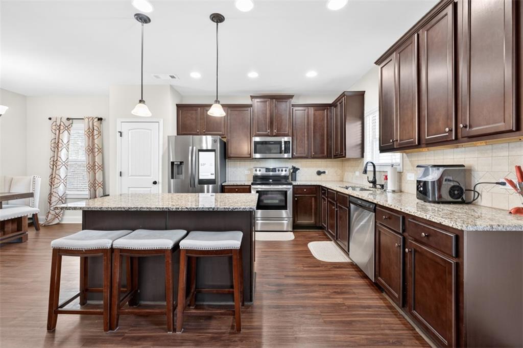 860 Tranquil Way Hampton, GA 30228 - Photo 15 of 54 a kitchen with stainless steel appliances kitchen island granite countertop a table chairs in it and wooden floors