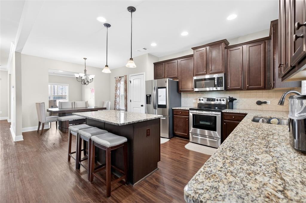 860 Tranquil Way Hampton, GA 30228 - Photo 16 of 54 a kitchen with stainless steel appliances kitchen island granite countertop a stove a sink a refrigerator and a wooden cabinets