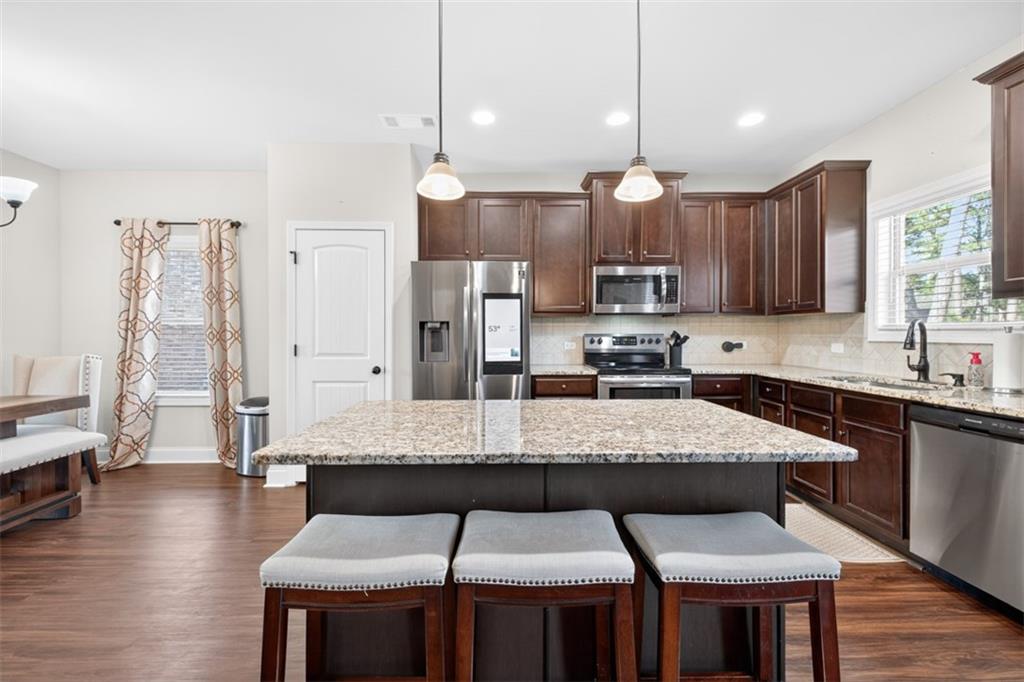 860 Tranquil Way Hampton, GA 30228 - Photo 17 of 54 a large kitchen with stainless steel appliances kitchen island granite countertop a table chairs sink and wooden floor