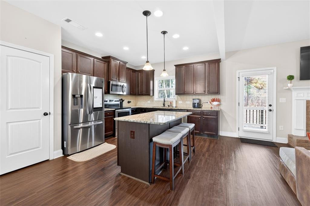 860 Tranquil Way Hampton, GA 30228 - Photo 18 of 54 a kitchen with stainless steel appliances granite countertop a refrigerator a stove top oven a sink dishwasher and a refrigerator with wooden floor