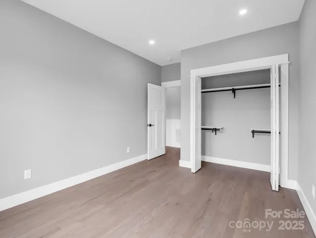 an empty room with wooden floor & closet area