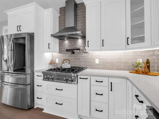 a kitchen with stainless steel appliances granite countertop white cabinets and a stove