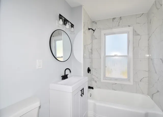 a bathroom with a bathtub shower sink and mirror