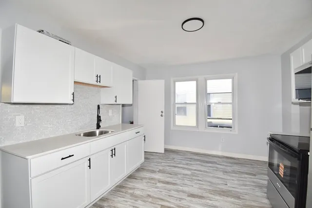 a kitchen with a sink cabinets wooden floor and a window