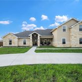 a view of a white house next to a yard and large trees
