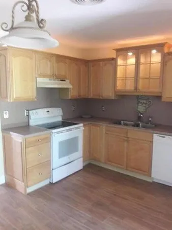 a kitchen with a white cabinets and wooden floor