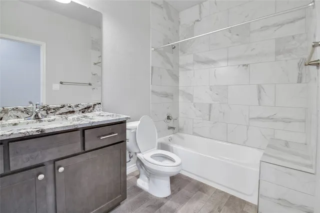 a bathroom with a granite countertop toilet a sink and a bathtub