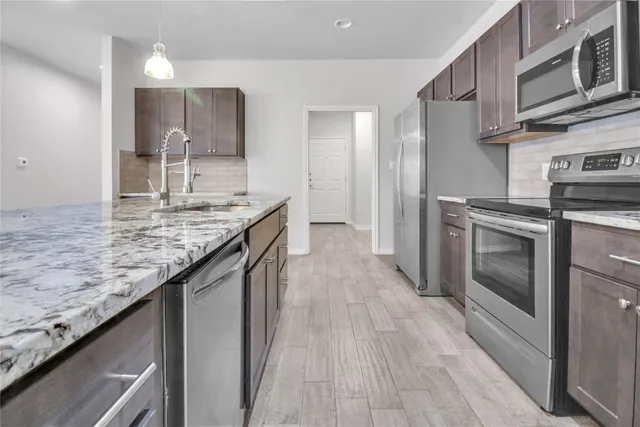 a kitchen with stainless steel appliances granite countertop a kitchen island hardwood floor sink and stove