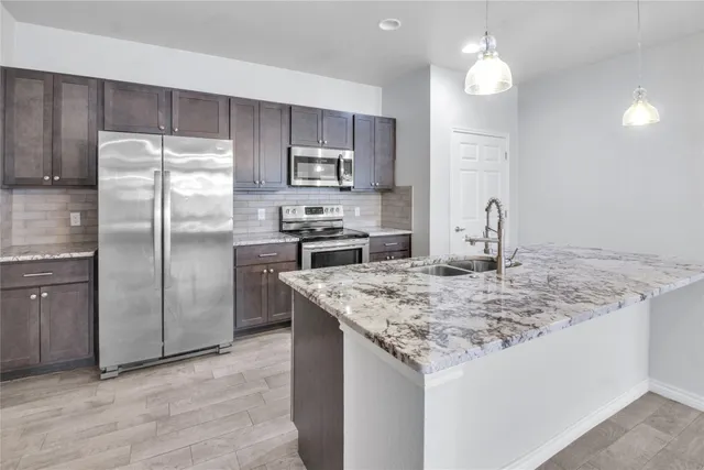a kitchen with kitchen island granite countertop a sink stove and refrigerator