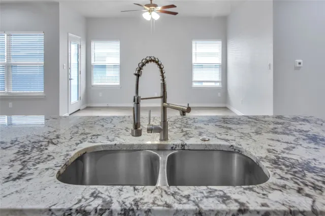 a kitchen with a sink granite counter tops and a view of living room