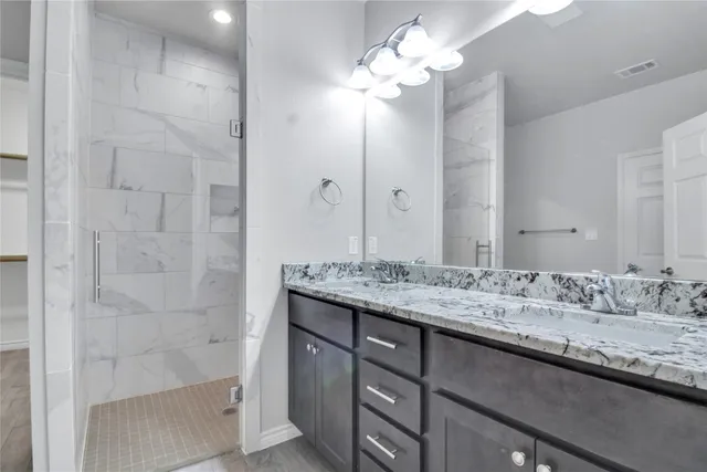 a bathroom with a granite countertop sink a large mirror and a shower