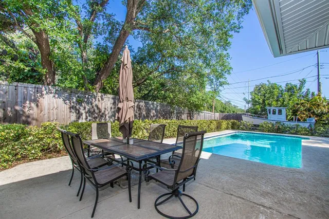 a view of a patio with table and chairs potted plants and floor to ceiling window
