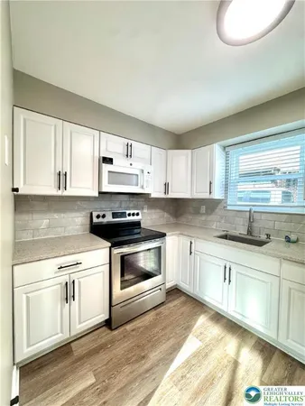 a kitchen with stainless steel appliances granite countertop a stove a sink and white cabinets