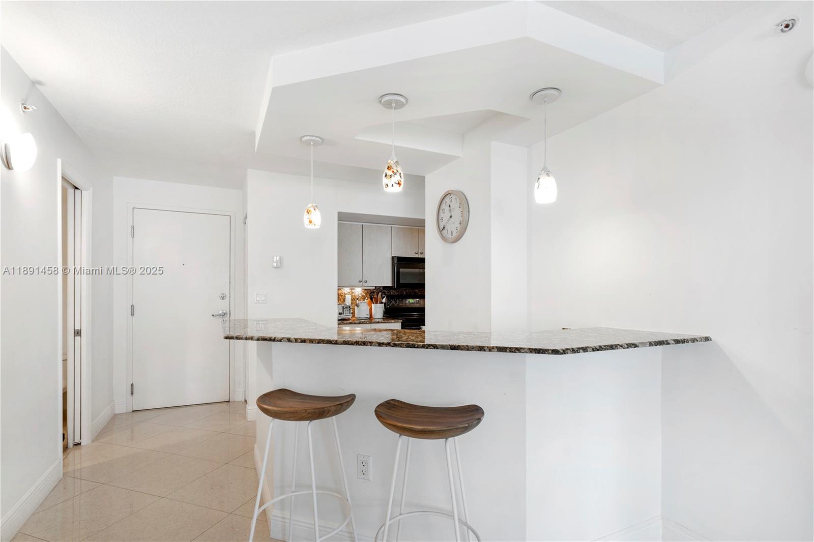 6917 Collins Avenue, Unit 508 Miami Beach, FL 33141 - Photo 5 of 18 a kitchen with granite countertop a sink and a refrigerator