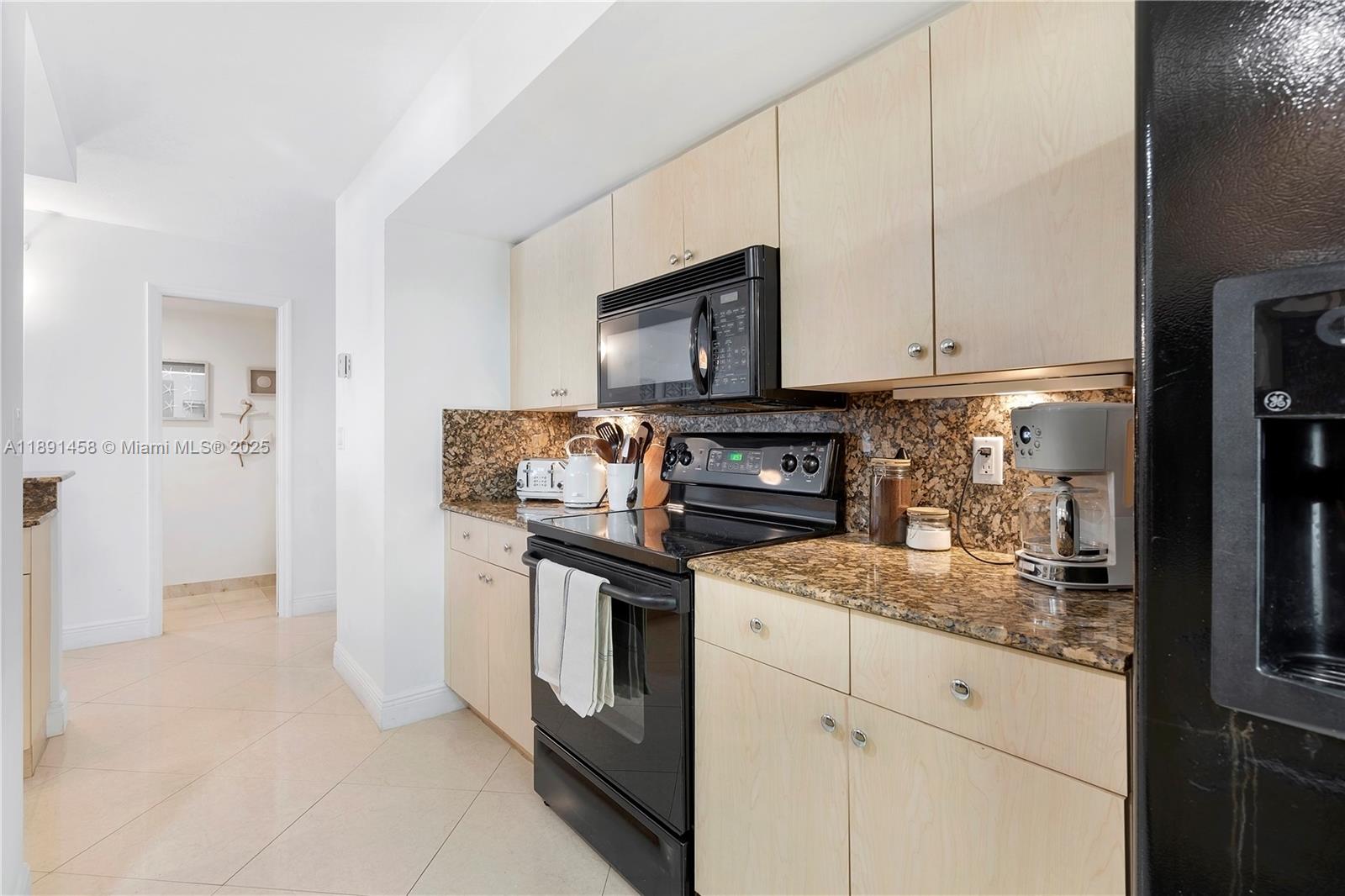 6917 Collins Avenue, Unit 508 Miami Beach, FL 33141 - Photo 7 of 18 a kitchen with stainless steel appliances granite countertop a stove a microwave and a refrigerator